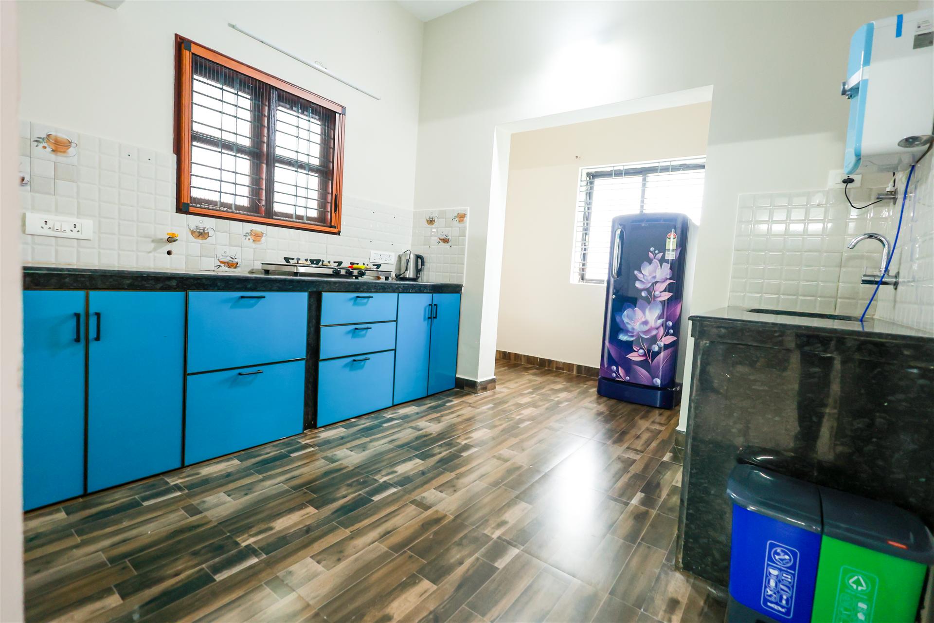 Modern kitchen with blue cabinets, gas stove, refrigerator and wooden floor